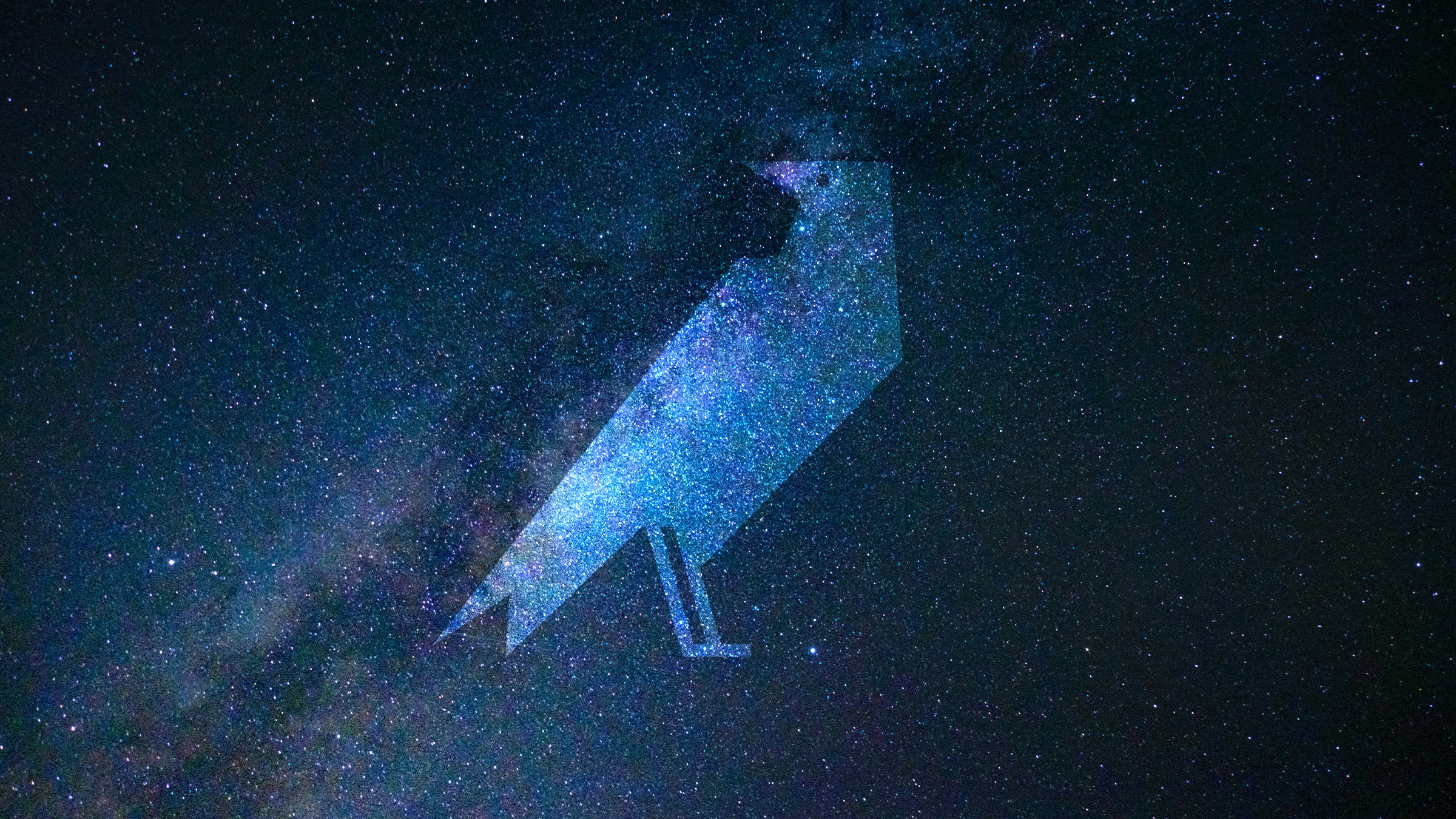 Stylized geometric silhouette of a crow, representing the logo of Crow’s Theatre, centred against a deep blue star-filled galaxy background. The crow shape is semi-transparent, allowing the cosmic texture to show through.