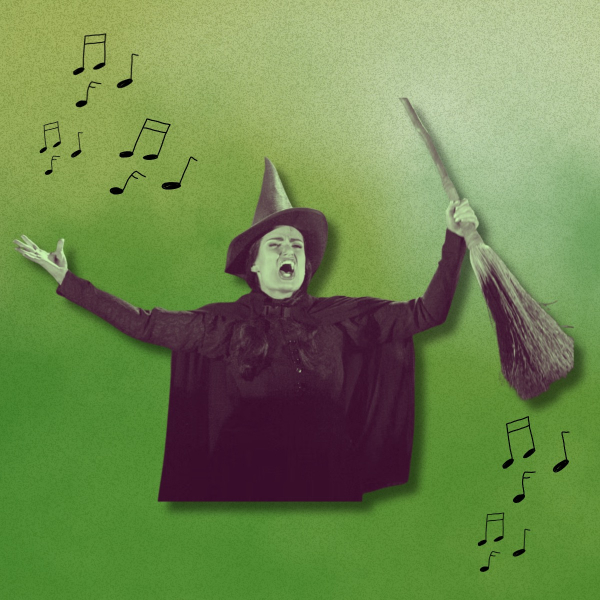 A person dressed as a green-skinned witch wearing a black pointed hat and cape stands against a green background, mouth open wide as if singing or shouting. One arm is raised holding a broomstick, while the other is extended outward. Black musical notes are illustrated around the figure, suggesting singing.
